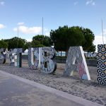 Buchstaben der Stadt Setúbal im Sand mit dem Meer im Hintergrund