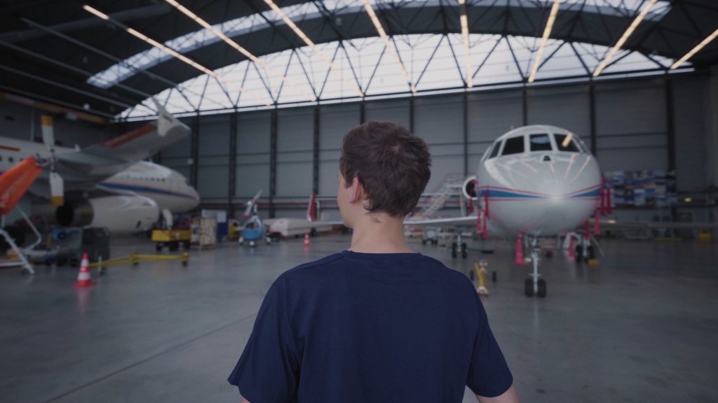 Young Engineer vor einem Flugzeug in einem Hanger