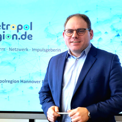 Christoph Meineke, Geschäftsführer der Metropolregion Hannover, vor einer blauen Leinwand mit einer Präsentation von der metropolregion.de