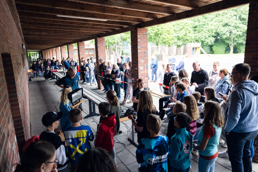 Schüler stehen an der Rennstrecke unter dem Vordach der Schule.